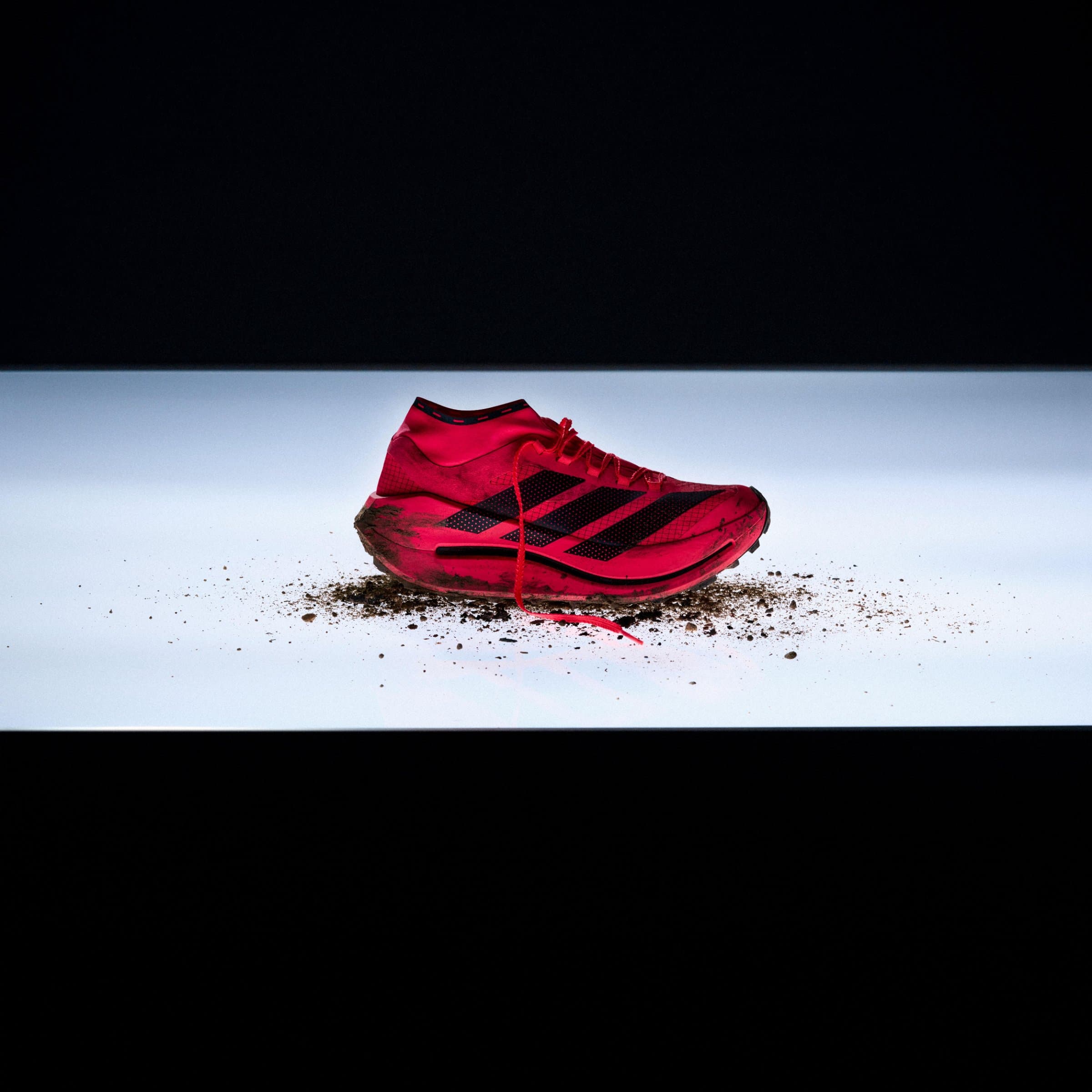 Scarpa da trail running ad alte prestazioni su sfondo roccioso alpino con illuminazione drammatica laterale