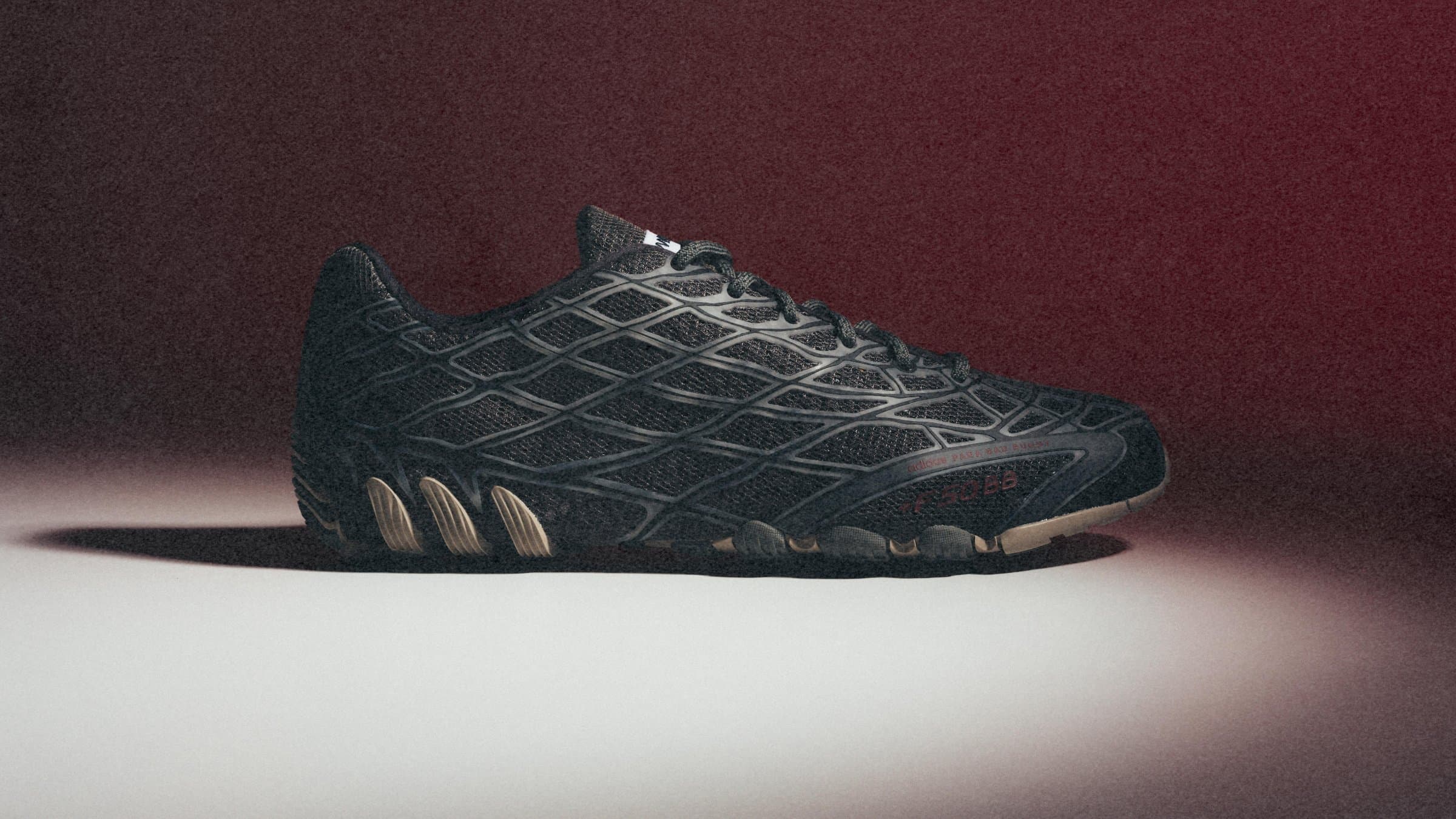 Adidas F50 Ghost Sprint colorway nero con gabbia strutturale Araña su sfondo scuro, vista laterale editoriale