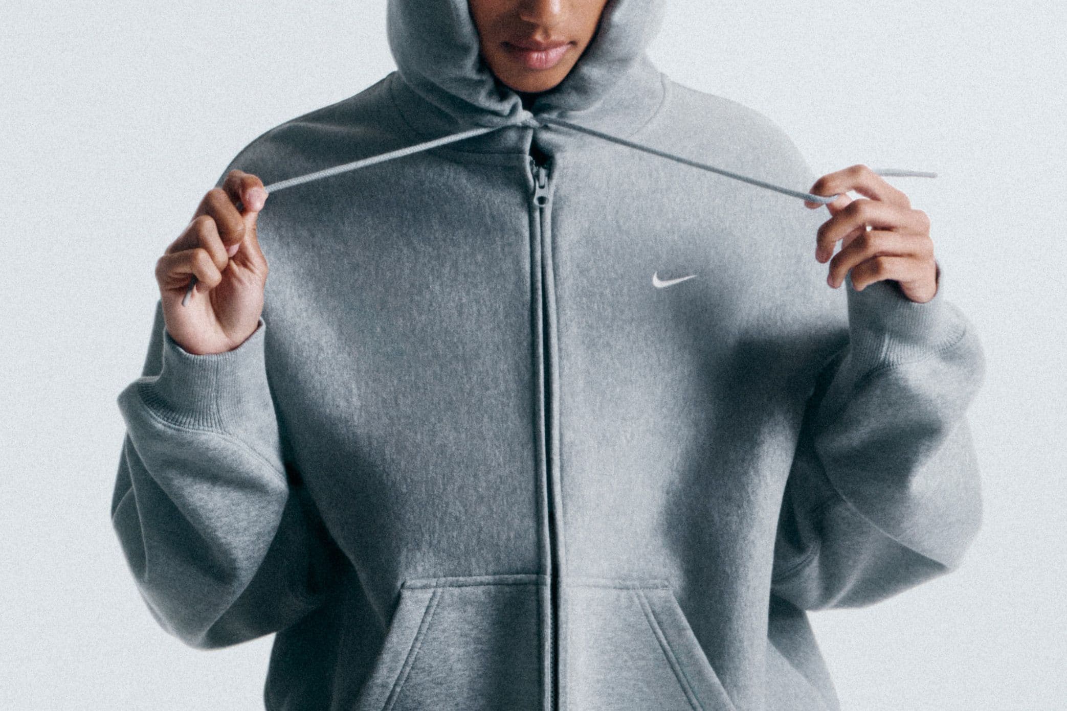 Felpa oversize grigia e nera su sfondo neutro chiaro, illuminazione morbida da studio, stile editoriale sportswear femminile