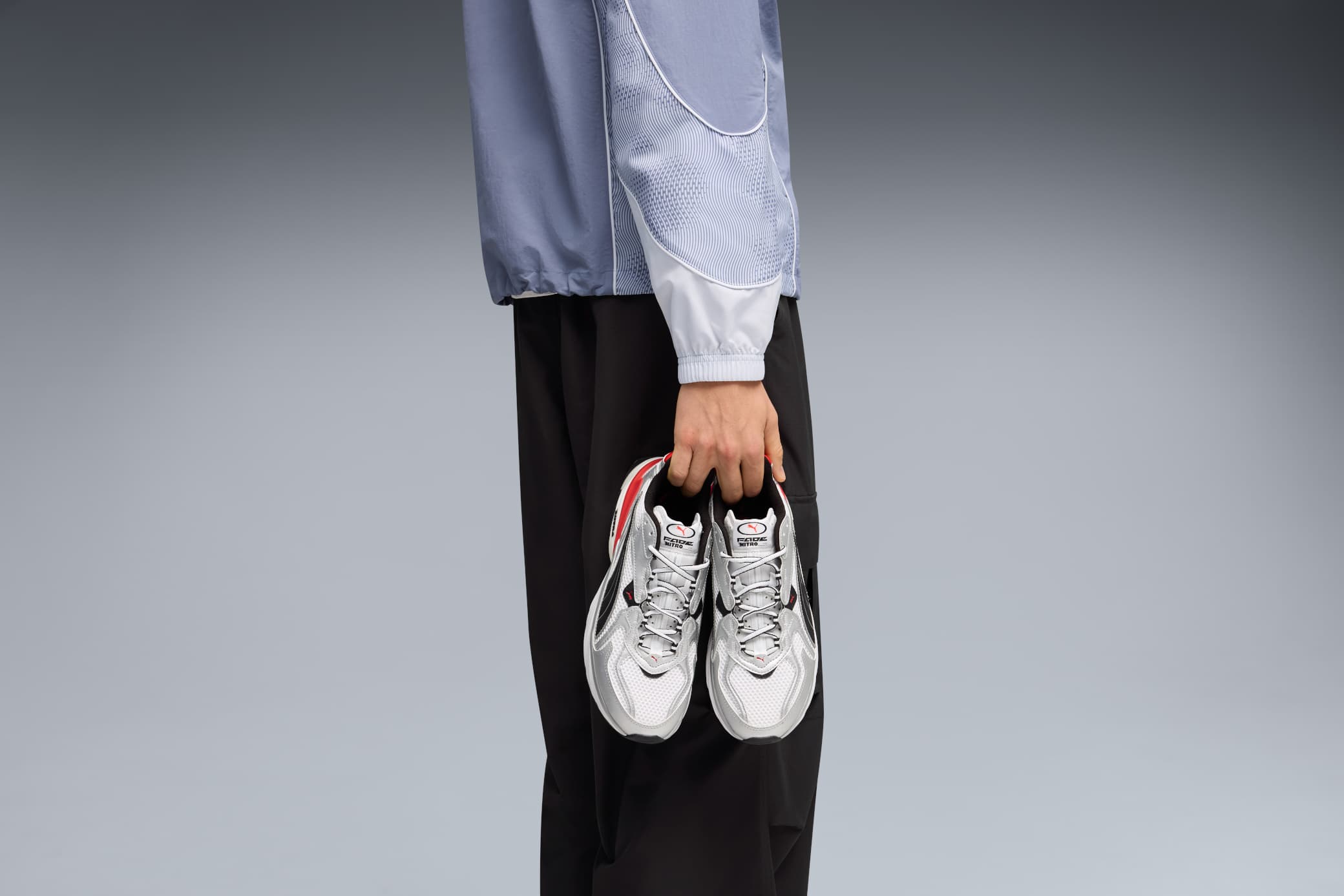 Sneaker tecnica da running con suola spessa e tomaia leggera su sfondo urbano, styling streetwear